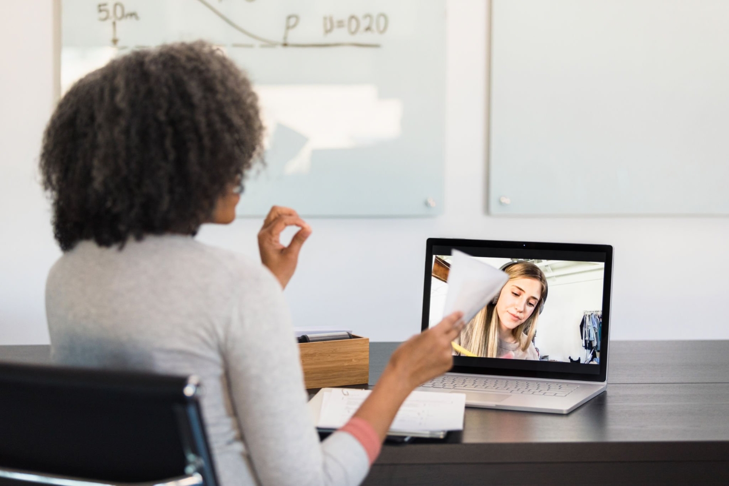Unrecognizable female tutor helps young adult woman via video conferencing